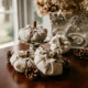 A set of 4 linen pumpkins with cinnamon sticks as their stems are photographed in front of a window.