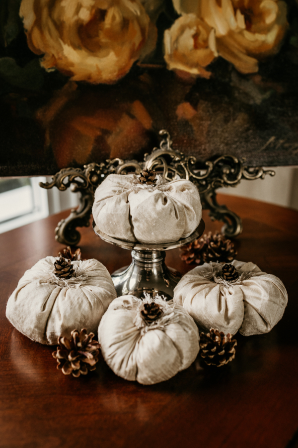 Photographed in this picture are 4 silk pumpkins topped with mini pinecones.