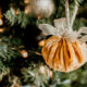 An golden velvet ball with a gold bow hanging on a Christmas tree